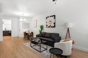 A modern living room with a sofa, coffee table, and a painting of a flower.