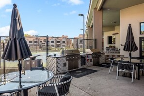Un área de patio al aire libre con una parrilla, asientos y sombrillas.