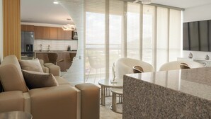 A modern living room with a sofa, a coffee table, and a TV. There is a kitchen area with cabinets and a refrigerator. - Matiz 1701 (Dosquebradas)