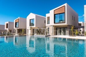 A modern hotel with a swimming pool, featuring contemporary architecture and clear skies. - Avalon Gardens Villa 13 (Emba)