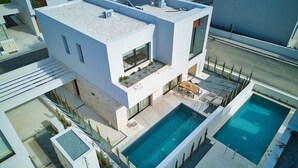 A modern two-story building with a rooftop terrace, a swimming pool, and a landscaped garden. - Avalon Gardens Villa 13 (Emba)