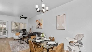 A dining area with a glass table, brown chairs, and a high chair. - Modern2BR Pickle&Basketball Ct,Pool,BBQ Cabanas (Scottsdale)