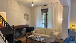 A living room with a sofa, a coffee table, a TV, and a fireplace.