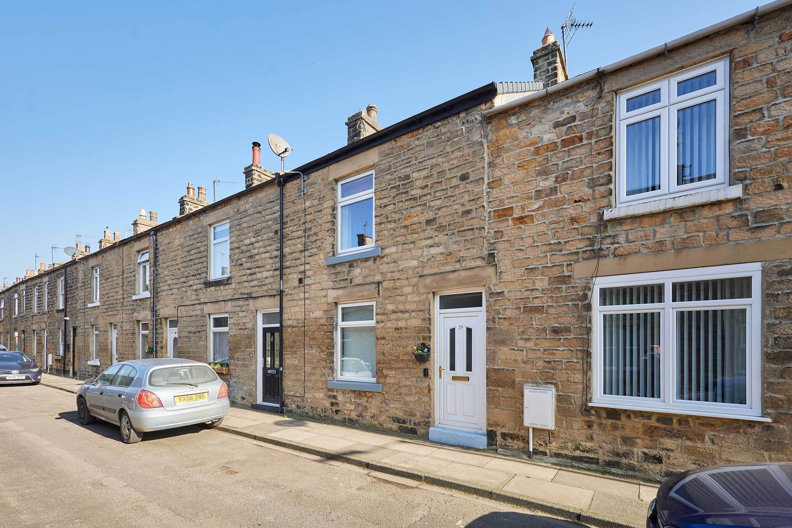 A row of terraced houses with a car parked in front.