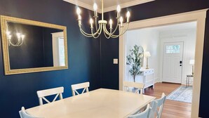 A dining room with a white table and chairs, a chandelier, and a large mirror on the wall. - White Lily Cottage, White Lily Cottage (St. Augustine)