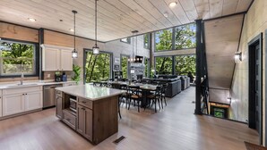 A spacious kitchen with wooden cabinets, a central island, and a dining area with chairs and a table.