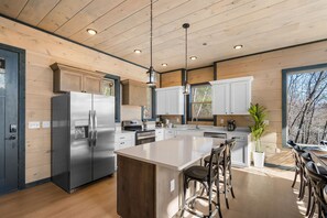 Una cocina moderna con paneles de madera, electrodomésticos de acero inoxidable y una isla central con taburetes de bar.
