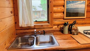 Cocina de cabaña de madera con un lavamanos, una ventana y un cuadro en la pared.