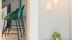 A modern kitchen with a marble backsplash, a round mirror, and a green bar stool. - Oasis de Lujo para descansar en Pereira (Pereira)