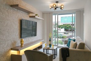 Relax in this stylish living room with a flat-screen TV, sofa, and chair, offering a view of the city.