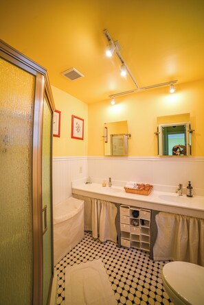 Un baño con una pared amarilla, un lavamanos blanco, un inodoro y una ducha.