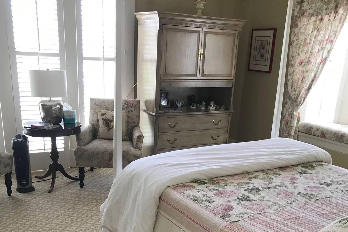 Une chambre à coucher avec un grand lit, une commode, une chaise et une table.