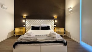 Een moderne hotelkamer met een groot bed, twee nachtkastjes en een donkere accentmuur.