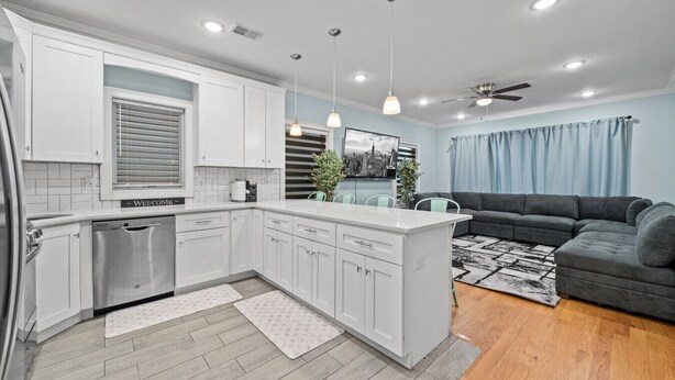 Una cocina moderna con armarios blancos, lavavajillas integrado e iluminación colgante.