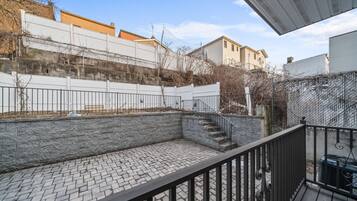 A courtyard with a stone wall, a metal fence, and a staircase leading to a higher level.
