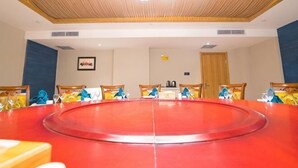 Un salón de conferencias con una gran mesa redonda, sillas y techo de madera.