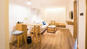 Un espacio habitable compacto con sofá, escritorio pequeño, silla y televisor.