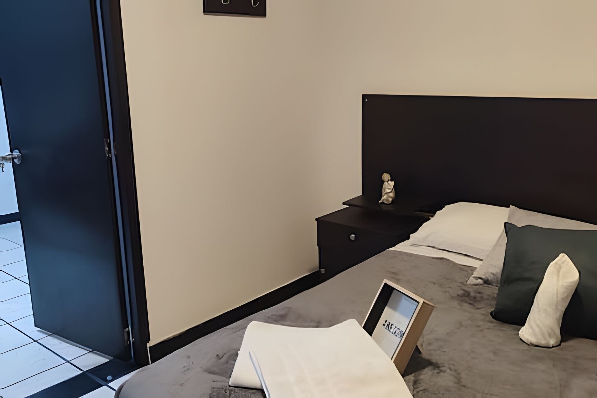 A modern bedroom with a bed, nightstand, and a small statue.
