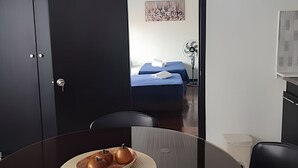 Ein Hotelzimmer mit Bett, Schreibtisch, Stuhl und Esstisch mit Obstschale.