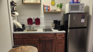 Eine kleine Küche mit Holdekor-Schränken, einem Edelstahl-Kühlschrank, einer Mikrowelle und einer Kaffeemaschine.