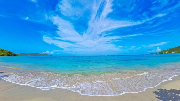 Una playa con agua azul cristalina y una orilla arenosa.