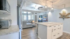 Una cocina moderna con una isla central, electrodomésticos integrados e iluminación colgante.