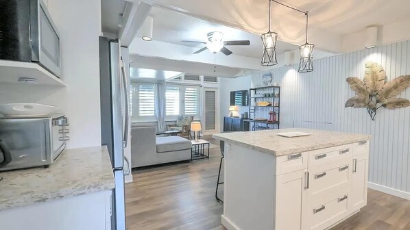 A modern kitchen with a central island, built-in appliances, and pendant lighting.