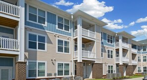 Un immeuble d’appartements à plusieurs étages, doté de balcons, de fondations en briques et de grandes fenêtres.