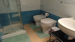 Une salle de bain avec une douche à parois de verre, un bidet, des toilettes et un lavabo avec un miroir.