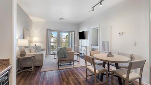 A modern hotel room with a dining area, a sofa, a TV, and a balcony with a view. - Landing | Stunning 1BD, Gym (North Las Vegas)