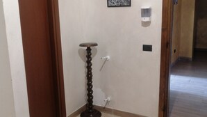 A hallway with a marble floor, a wooden door, a small round table, and a framed picture on the wall. - Malik di Bendesh Bibi (Verdellino)