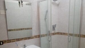 A bathroom with a glass-enclosed shower, a sink with a mirror above it, and a toilet. - Malik di Bendesh Bibi (Verdellino)