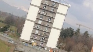A multi-story residential building with balconies, a parking lot, and a crane in the background. - Malik di Bendesh Bibi (Verdellino)