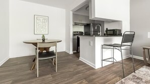 Une cuisine compacte comprenant un coin repas, un petit îlot central et un four à micro-ondes.