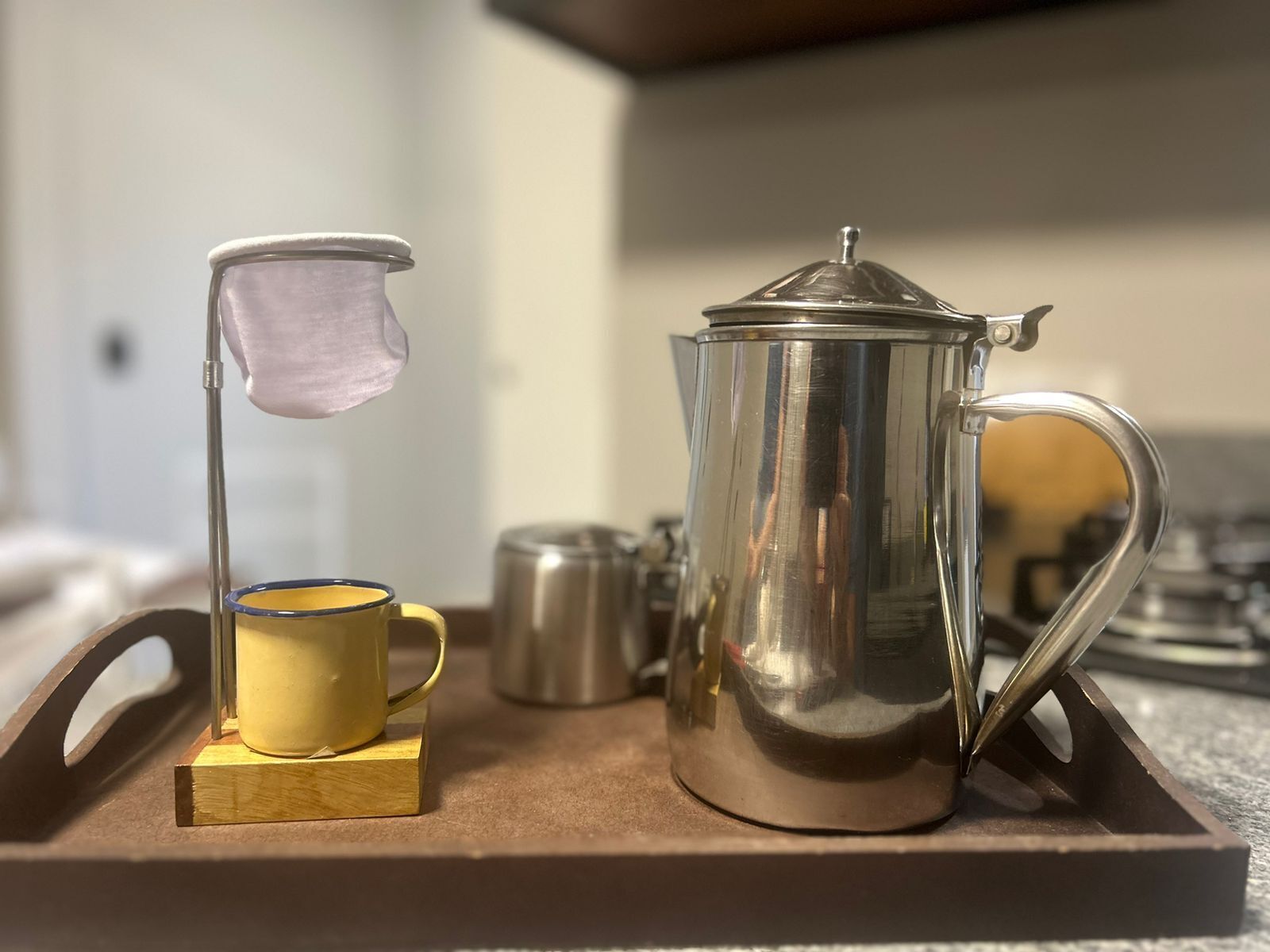 Eine Kaffeemaschine, eine gelbe Tasse und eine Flagge auf einem Tablett.