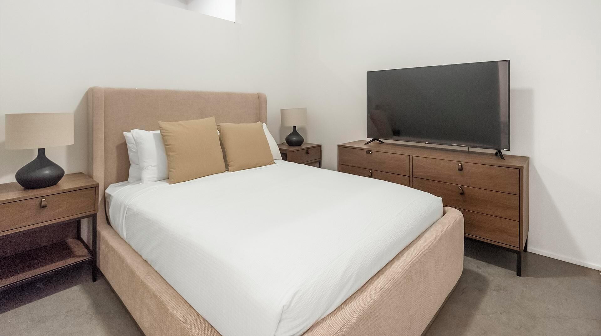Een hotelkamer met een bed, nachtkastjes, een televisie en een dressoir.