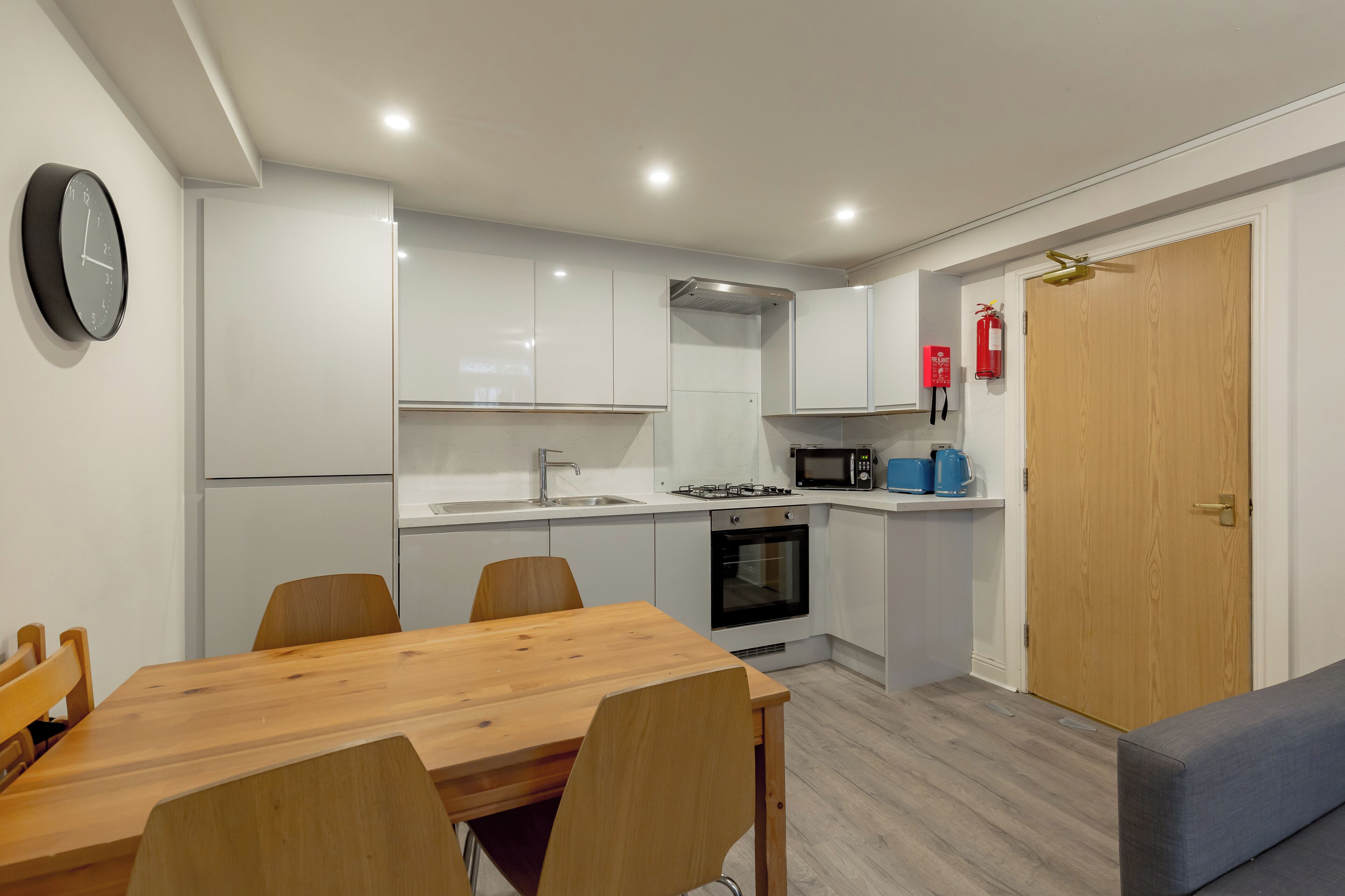 Une cuisine moderne avec des meubles blancs, une table à manger en bois et un four à micro-ondes.