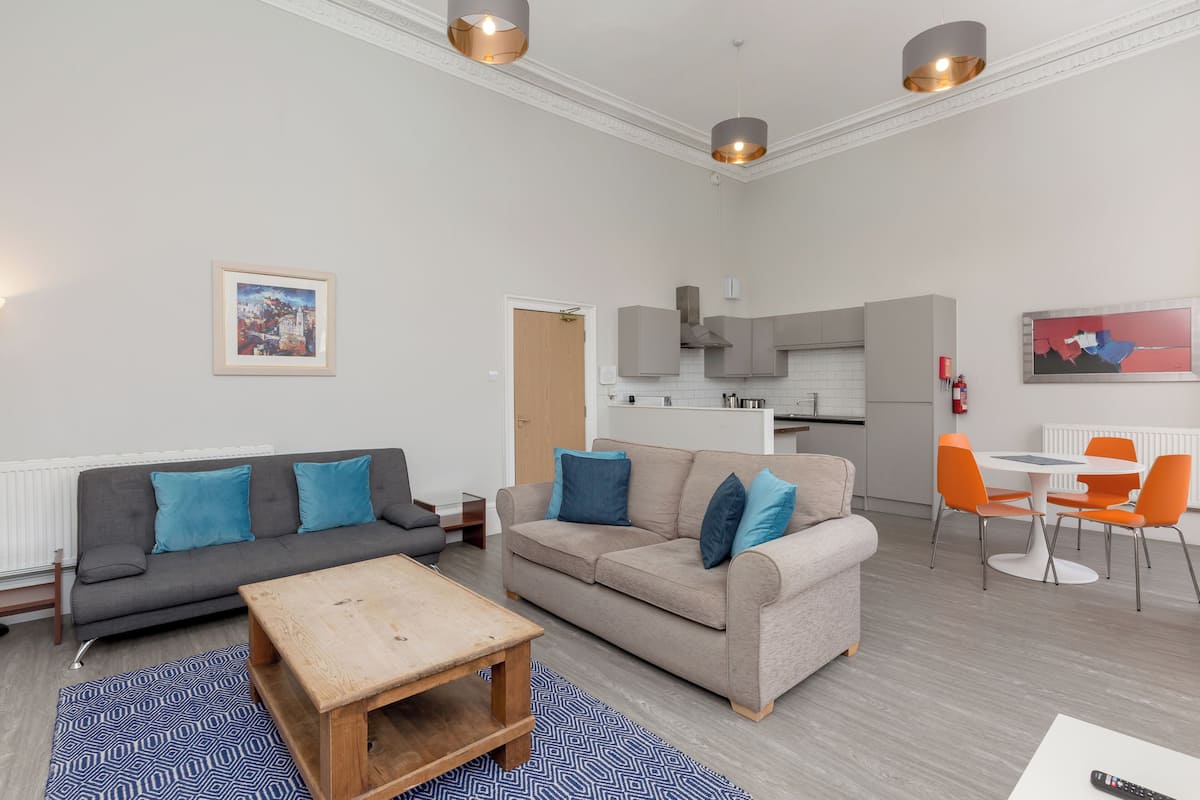 A modern living room with a sofa, a coffee table, and a dining area with chairs and a table.