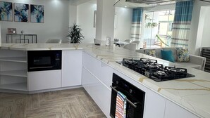 Una cocina moderna con una isla central, electrodomésticos integrados y un amplio ventanal con cortinas.