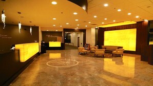 Un hall d’hôtel comprenant un comptoir d’accueil, un espace salon et un grand mur illuminé.
