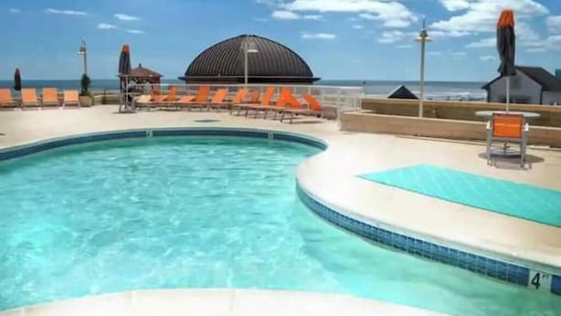 Une piscine avec des chaises longues et vue sur la plage.
