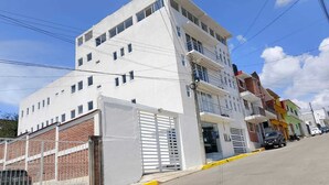 A multi-story building with a white facade, a gated entrance, and a yellow curb. - HOTEL ESTRELLA ZACATLAN (Zacatlán)