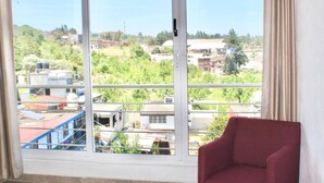 A room with a large window offering a view of a residential area. - HOTEL ESTRELLA ZACATLAN (Zacatlán)