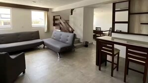A spacious living area with a sofa, a dining table with chairs, and a staircase leading to an upper level. - HOTEL ESTRELLA ZACATLAN (Zacatlán)