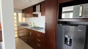 A modern kitchen with dark wooden cabinets, a stainless steel refrigerator, and a built-in microwave. - HOTEL ESTRELLA ZACATLAN (Zacatlán)
