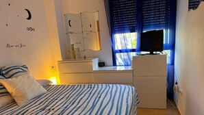 A bedroom with a bed, a desk, a TV, and a window with curtains. - Apartment in Playa de Piles ( Valencia ) 3 min from the beach (VC)