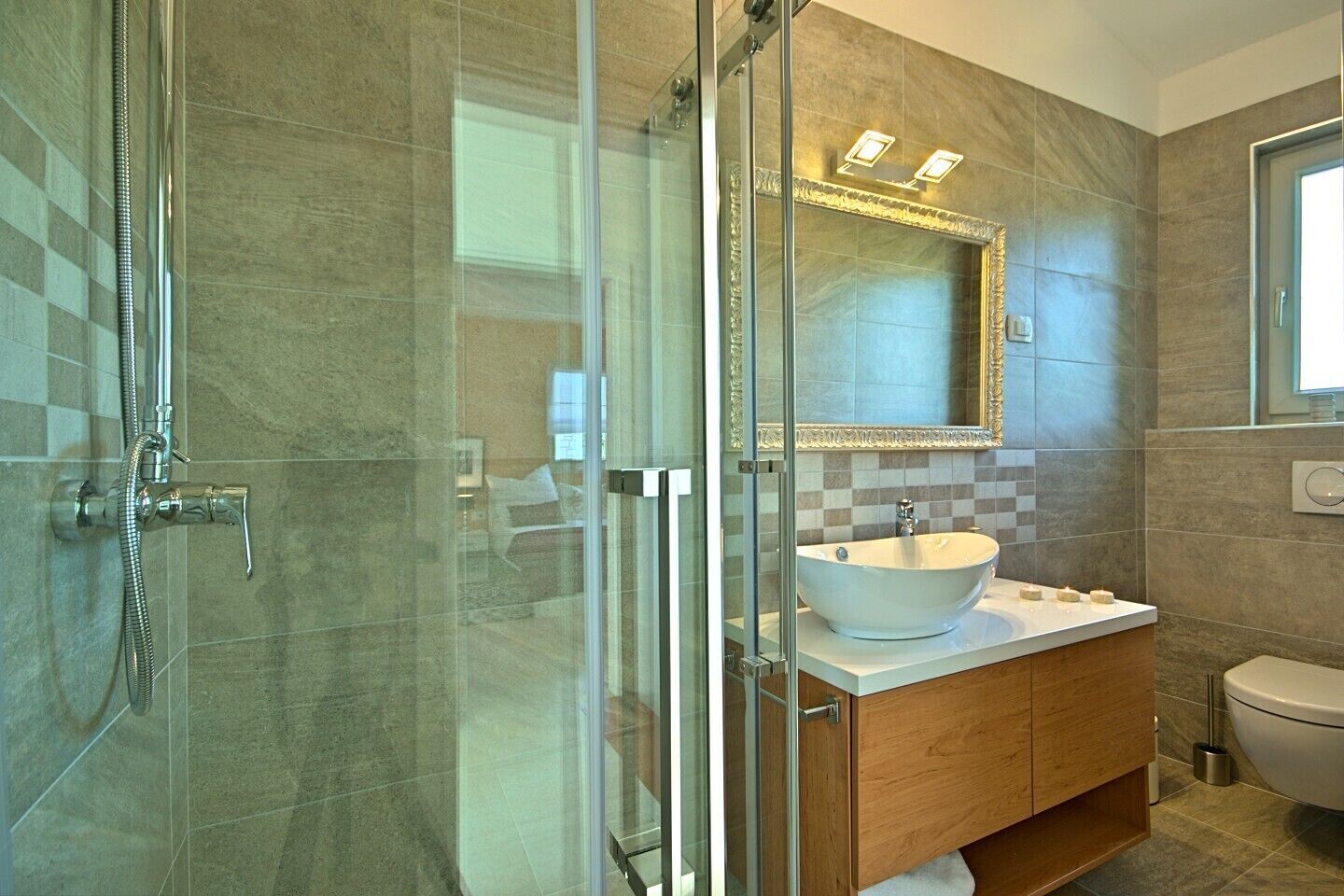 A modern bathroom with a glass-enclosed shower, a white sink, and a wooden vanity.