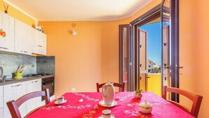 A dining area with a red tablecloth, white tableware, and a view through an open door to the outside.
