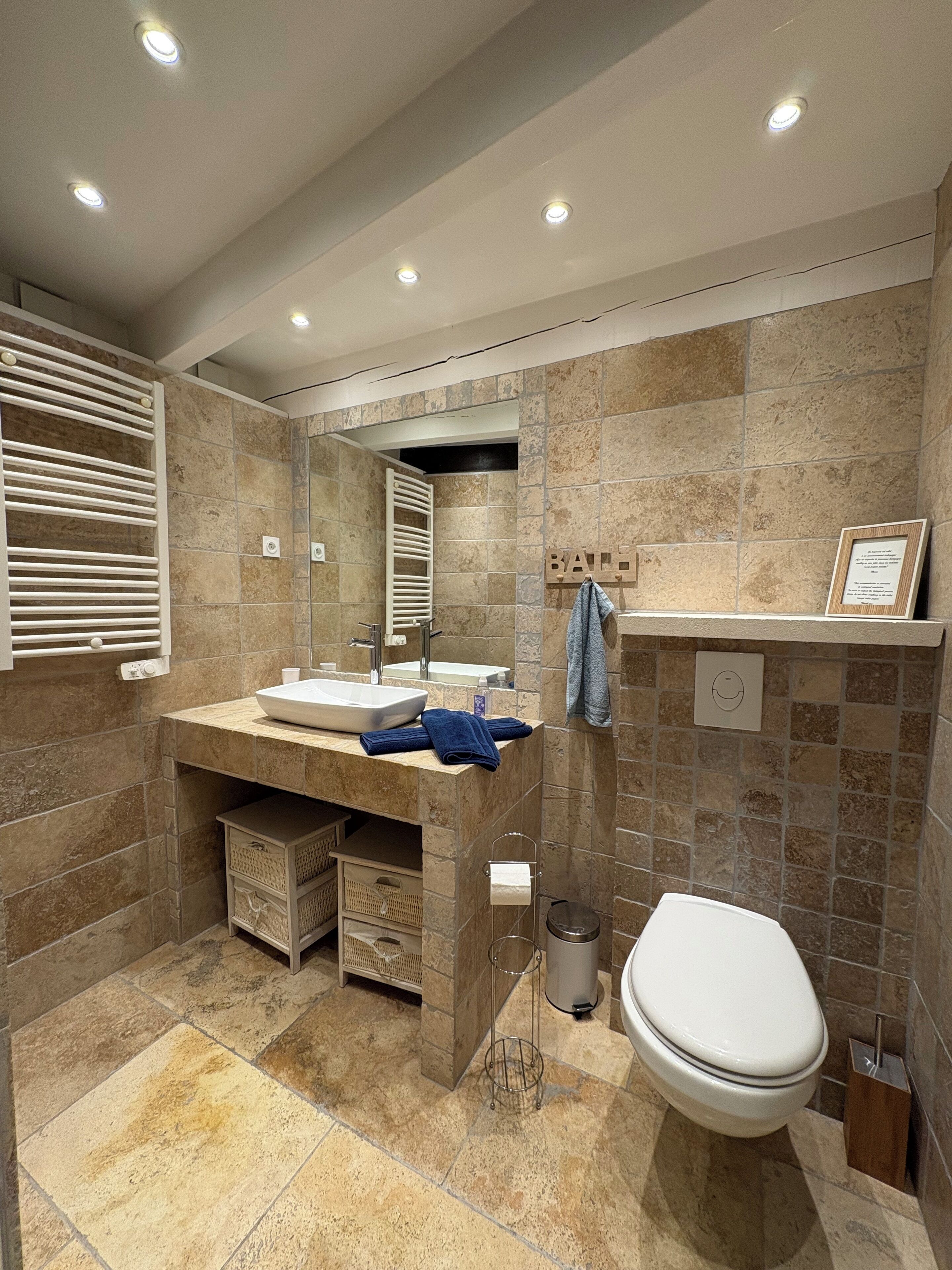 A modern bathroom with a built-in sink, a toilet, and a towel rack.