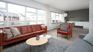 A modern living room with a leather sofa, a round coffee table, and a grey armchair.